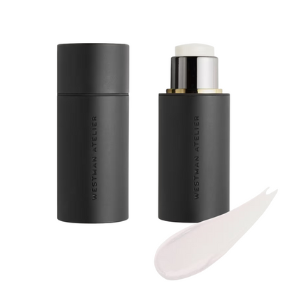 Black cosmetic stick with applicator and smear of cream on a white background, featuring the brand 'Westman Atelier'.